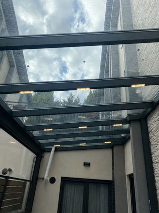 İç mekândan görülen sabit cam tavan ve koyu taşıyıcı profiller
