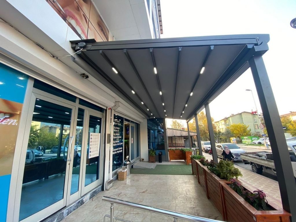 İşletme terası boyunca uzanan kumaş örtülü pergola ve taşıyıcılar
